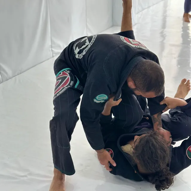Dos alumnos entrenando una técnica de control en el suelo durante una sesión de sparring