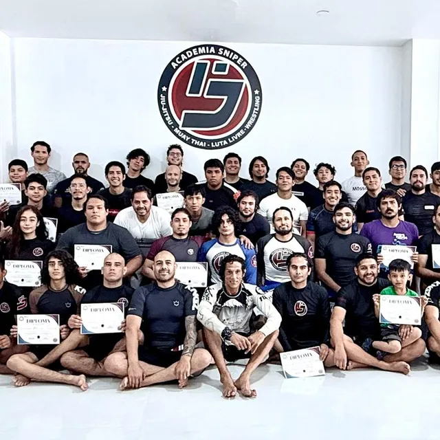 Gran grupo de alumnos posando con diplomas de graduación en el gimnasio
