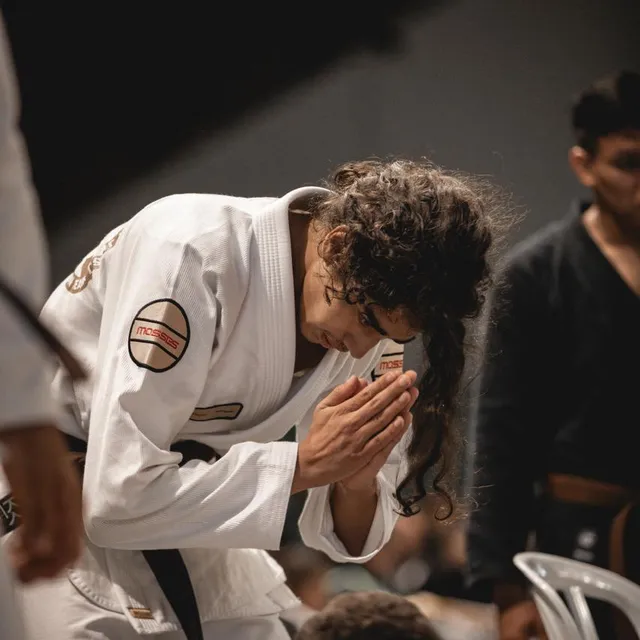 Competidor de cabello rizado con las manos juntas en gesto de respeto tras su combate