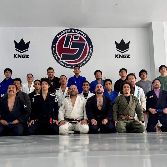Foto grupal de alumnos arrodillados y de pie frente a un mural de patrocinadores