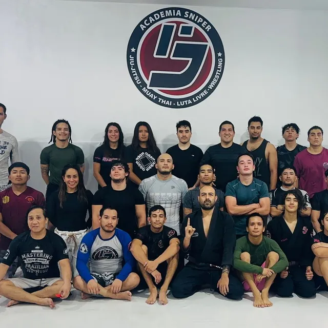 Grupo reducido de alumnos posando de pie frente al logo de la academia