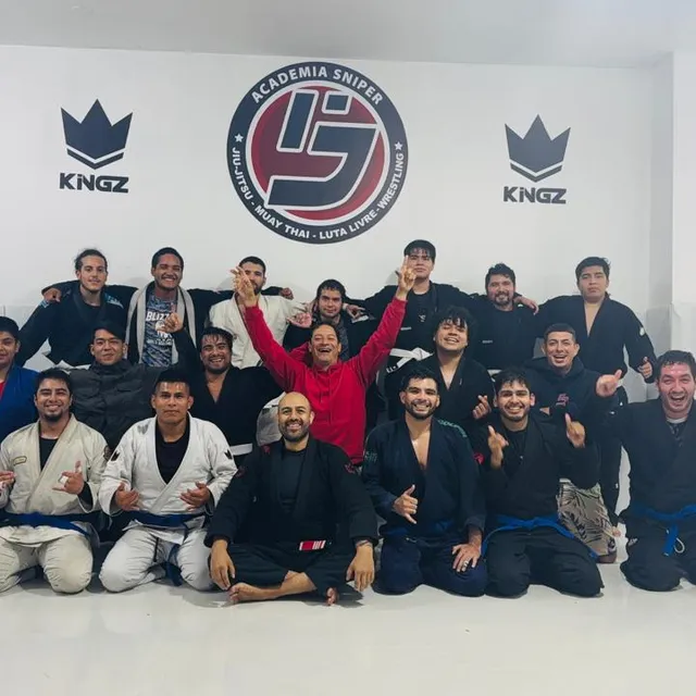 Equipo celebrando con los brazos en alto frente al logo del gimnasio