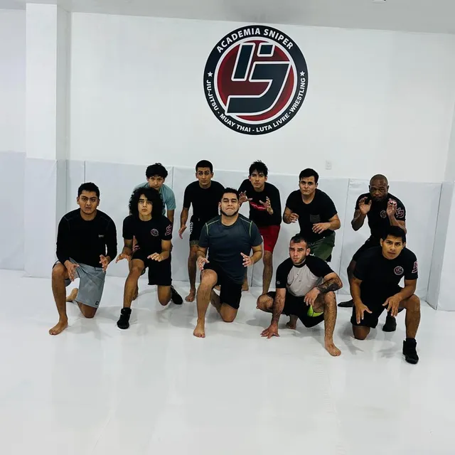 Equipo de competición posando con gesto serio frente al logotipo de la academia