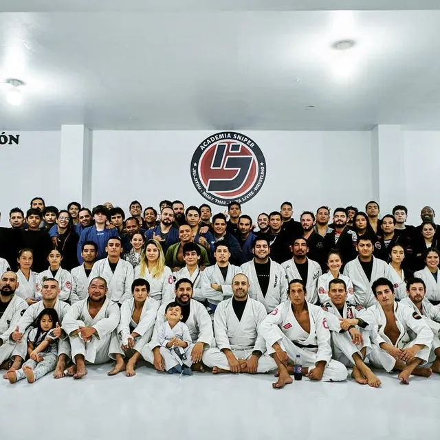 Fotografía grupal completa del equipo de jiu-jitsu con kimonos blancos en el gimnasio
