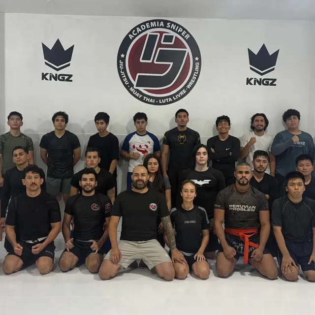 Foto grupal del equipo con alumnos y niños posando frente al mural de la academia