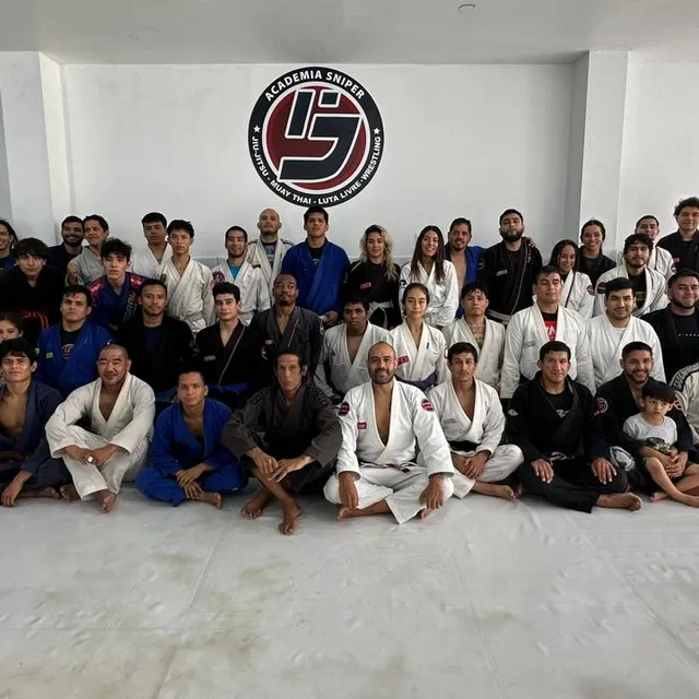 Foto grupal del equipo posando frente al logo del gimnasio junto a los murales de la academia