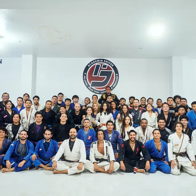 Foto grupal del equipo posando frente al mural de la academia, otra disposición del grupo