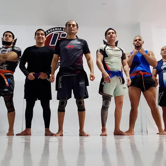Alumnos posan en fila con posturas dinámicas de combate frente a un fondo blanco