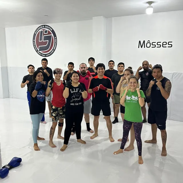 Grupo de alumnos de muay thai posando con los puños en alto tras la clase