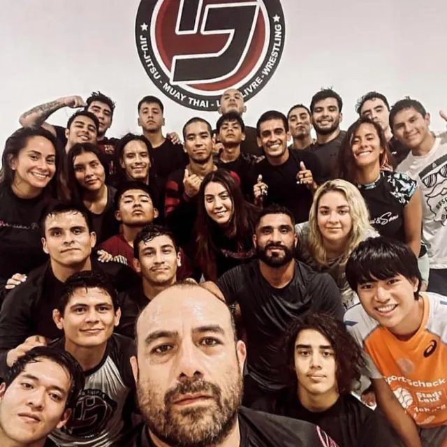 Selfie grupal del equipo tras un evento de grappling, con el instructor al frente
