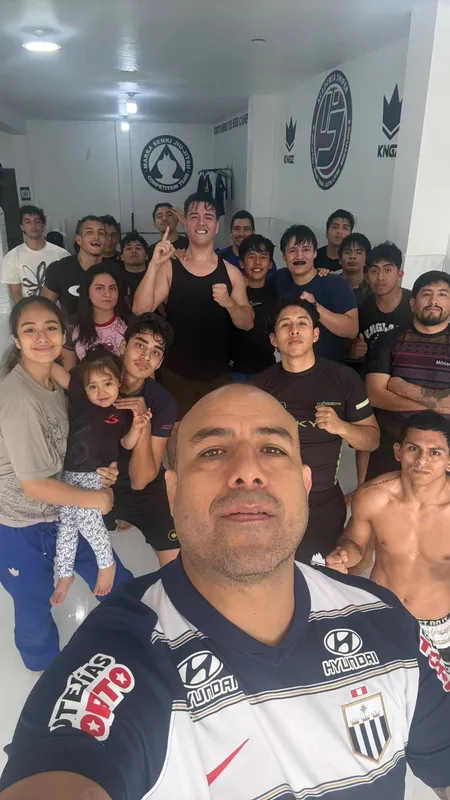 Selfie grupal del instructor Francisco Retamozo con todo el equipo frente al mural con los logos de la academia y de Marra Senki Jiu-Jitsu