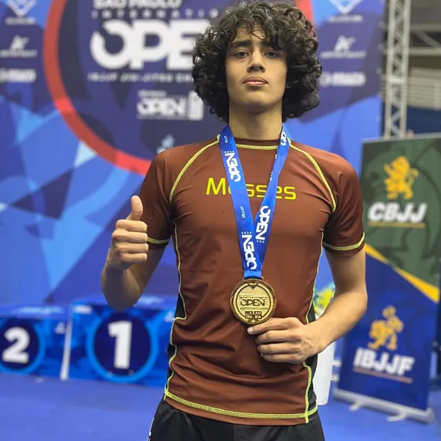 Competidor de cabello rizado sosteniendo una medalla de oro en el podio del São Paulo International Open