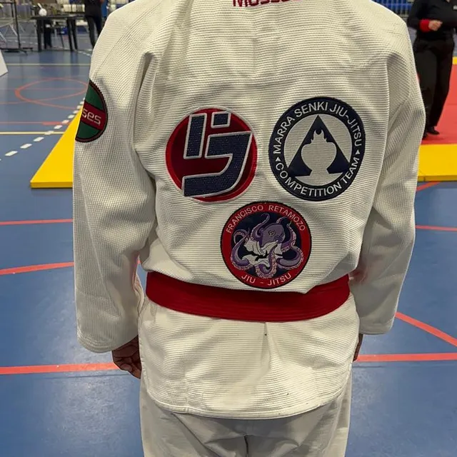 Vista trasera del kimono de un competidor con los parches de la academia en un evento de competencia